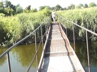 'Messalina clad in Sun. Outside Outdoor. Bare cougar ambles by bridge sea. Naturist naturist Woman'